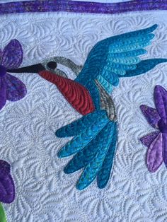 a quilted bird with purple flowers on it