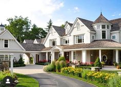 a large white house with lots of flowers in the front yard