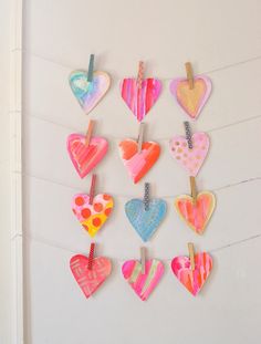 a bunch of heart shaped magnets hanging from clothes pins on a line in front of a white wall