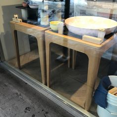 a wooden table sitting in front of a window next to a bowl and pane