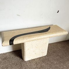 a stone bench sitting in the corner of a room with carpet on the floor and wall behind it