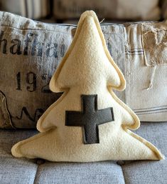 a christmas tree pillow sitting on top of a couch next to a pillow with a cross on it