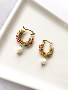 two pairs of colorful beaded hoop earrings on a white plate