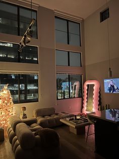 a living room filled with furniture and a christmas tree in front of two large windows