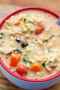 a red and white bowl filled with pasta soup