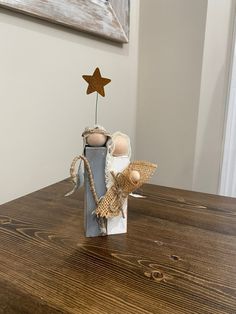 a small wooden angel sitting on top of a table next to a star shaped object