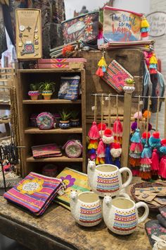 an assortment of colorful items on display in a market stall, including mugs and books