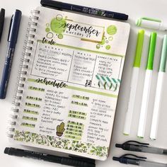 an open planner with pens and markers next to it