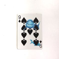 a playing card with blue fish and hearts on the back, in front of a white background