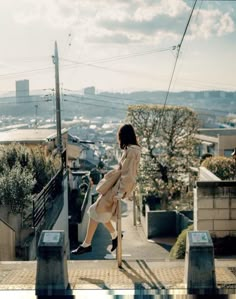 a woman walking up the side of a building on top of a wooden platform with power lines above her