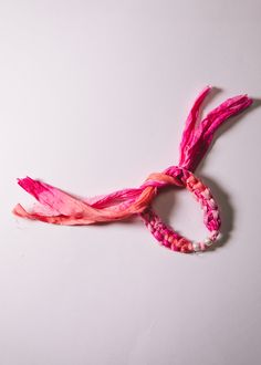 a piece of pink and red string on a white surface