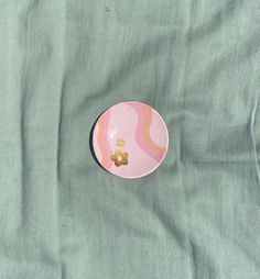 a pink and green plate sitting on top of a bed next to a blue sheet