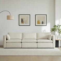 a white living room with two pictures on the wall and a couch in front of it