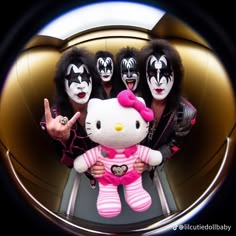 three people in black and white makeup are holding a hello kitty stuffed animal with pink stripes