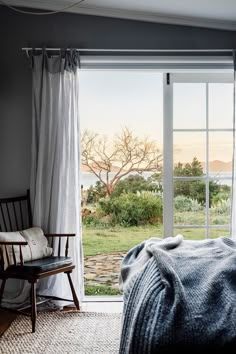 a bedroom with sliding glass doors leading out to the yard and ocean view from it's bed