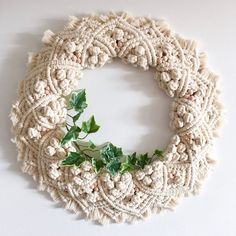 a wreath made out of yarn with ivy on the front and side, sitting on a white surface