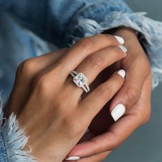 a woman's hand with a diamond ring on her left wrist and white nails