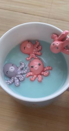 an octopus and other toys are in a bowl of water with blue liquid on the table