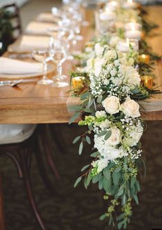 a long table with white flowers and greenery is set up for a formal dinner