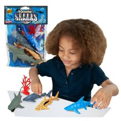 a young child playing with toys on a table in front of a bag of sharks