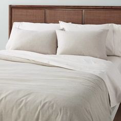 a bed with white linens and pillows on it's headboard in a bedroom