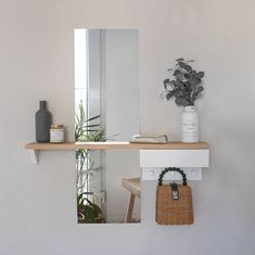 a mirror sitting on top of a wooden shelf next to a vase filled with flowers