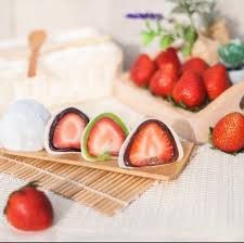 strawberries are cut in half and placed on a bamboo mat next to other fruit