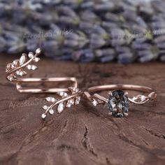 two wedding rings with leaves and crystals on the side, sitting on top of a piece of wood