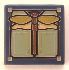 a blue and yellow tile with a dragonfly on it's back side in the center