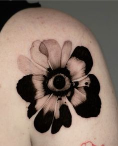 a woman's shoulder with a black and white flower tattoo on it