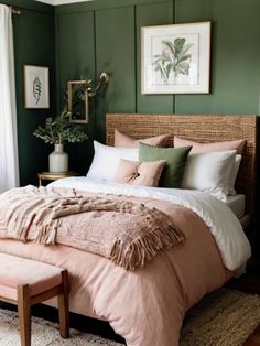 a bedroom with green walls and a bed covered in pink sheets, pillows and blankets