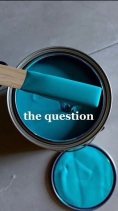 a blue paint can with the words the question painted on it and a wooden spatula