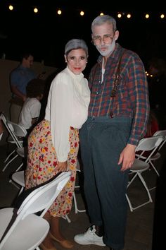 a man and woman standing next to each other in front of white folding chairs at an event