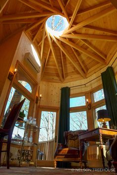 a living room filled with furniture and lots of windows under a wooden ceiling mounted skylight