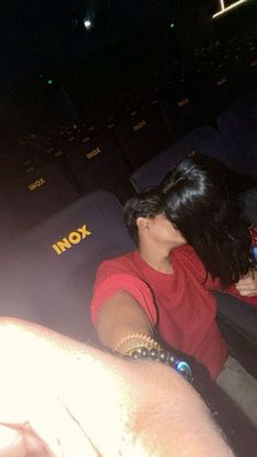 two people are sitting in an auditorium with their backs turned to the side, and one person is holding her hand out