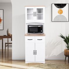 a microwave oven sitting on top of a white cabinet next to a potted plant