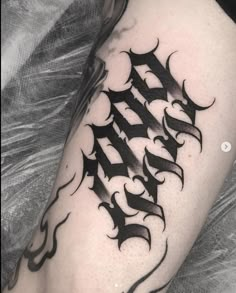 a black and white tattoo on the leg of a man's arm with letters