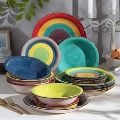 a table topped with plates and bowls filled with different types of colorful dishes on top of each other