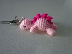 a crocheted keychain with a pink dragon on it's side