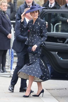 a woman in a blue dress and hat walking next to a man