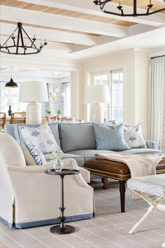 a living room with couches, chairs and lamps on the ceiling in front of windows