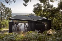 a house with a solar panel on the roof and table in the foreground surrounded by trees