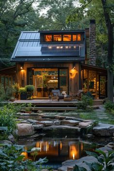 a small house with a pond in the front yard and lots of greenery around it