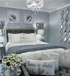 a bedroom with gray walls and white bedding, chandelier and pillows on the headboard