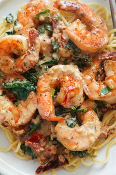 pasta with shrimp, spinach and tomato sauce in a white bowl on a table