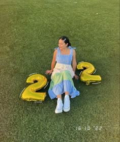 a woman sitting in the grass next to numbers that spell out 2, 3, and 4