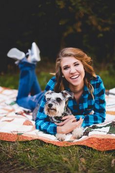 a woman laying on top of a blanket holding a dog