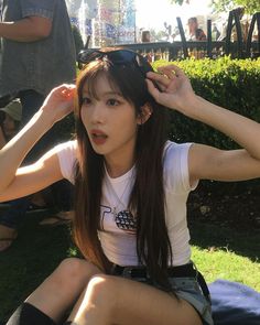 a young woman sitting on the ground with her hair in ponytails and sunglasses over her head