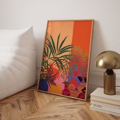 an orange and pink painting sitting on top of a wooden floor next to a lamp