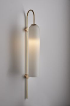 a wall light that is on the side of a wall with a white glass shade